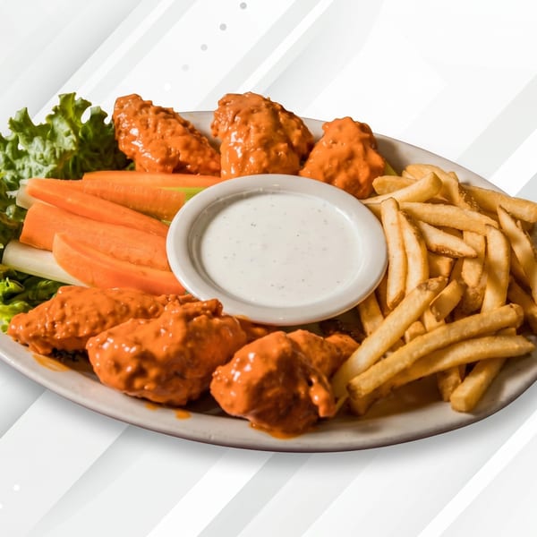 A plate of buffalo wings, french fries, carrot and celery sticks, and a side of ranch dressing.